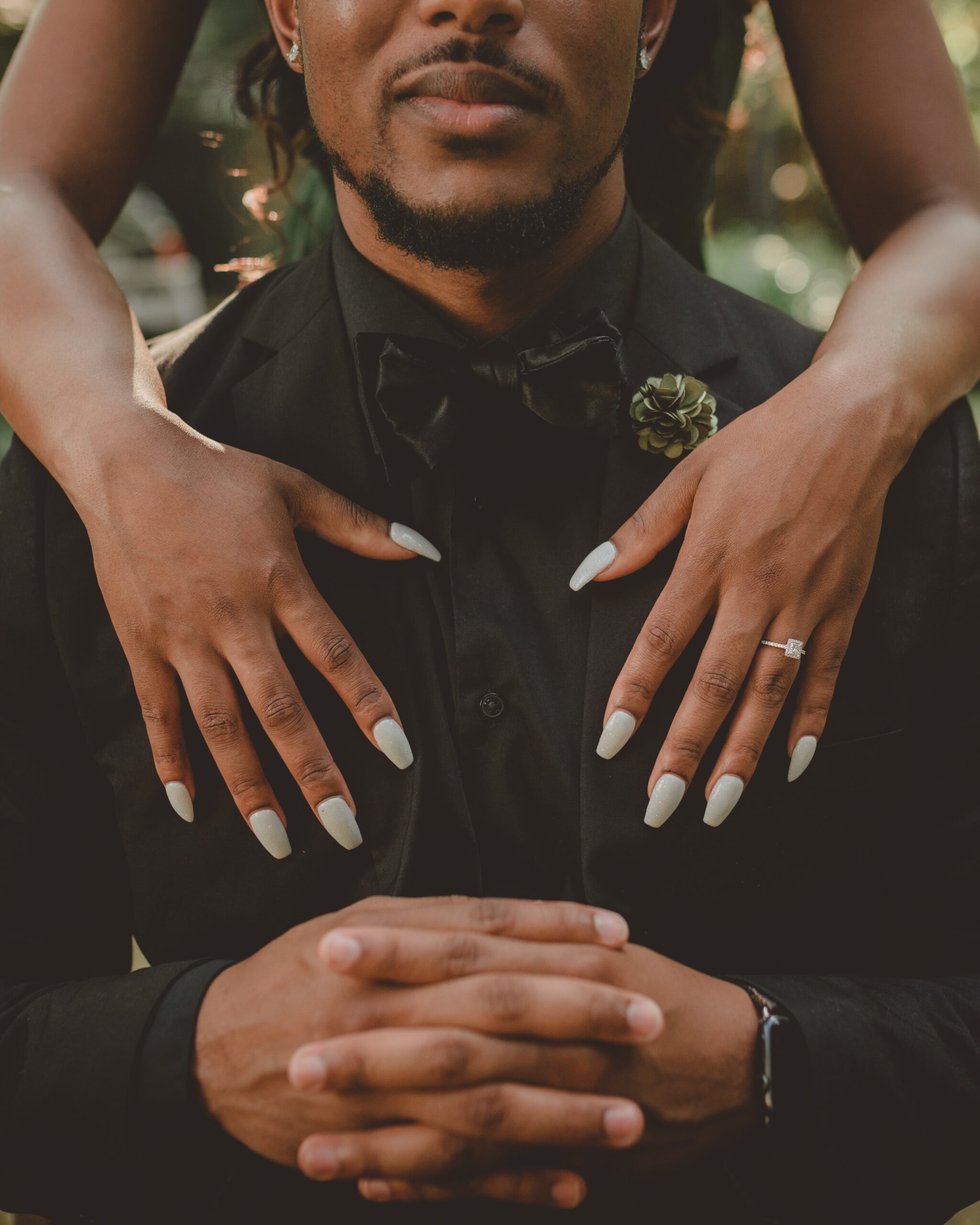 black woman with palm of hands on the chest of a black man. he is on a black suit.